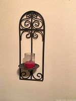 single black scroll metal wall sconce with glass cylinder and red candle