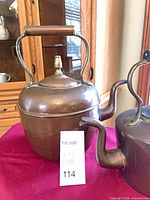 First copper kettle close-up showing wood handle and brass finial