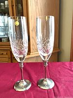 Two tall cut crystal flutes with silver-plated stems and bases