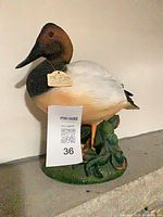 Front view of painted duck figurine with tag and MaxSold slip