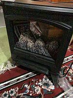 Front view of black electric fireplace stove showing glass door and simulated logs