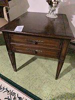 Front view of one end table showing drawers and tapered legs