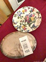 Top view of floral chintz plate beside silver-plated trivet