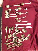 All teaspoons and spreaders laid out on red cloth