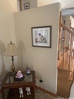End table positioned against wall showing lamp and decoration on glass top
