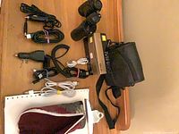 Overhead view of entire lot showing binoculars, Nikon charger box, camera bag, clipboard, eyeglass case and assorted cables
