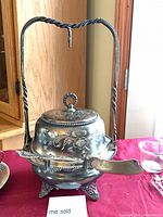 Full view of butter dish with lid closed, knife in holder, ornate stand visible