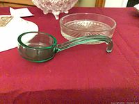 Green uranium glass ladle beside clear starburst dish