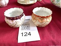 Pair of miniature porcelain pots with gilded rims and colored bands