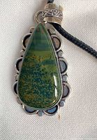 Front view of teardrop bloodstone pendant in sterling frame on black cord