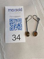 Earrings beside MaxSold card showing scale and weight information