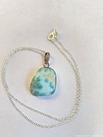 Necklace laid flat showing larimar pendant and chain