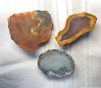 Three agate chunks on fabric showing colour variety