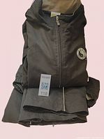 Folded black sweat suit showing jacket with zipper and logos