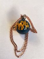 Pendant and chain coiled, close view of cloisonné motif