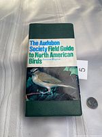 Front cover showing title band and bird image with coin for scale