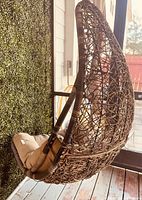Full view of hanging wicker egg chair on porch