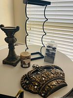 Crown, wine rack, candle holder, pillar candle and boxed candles on table
