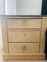 Front view of nightstand showing three drawers and hardware
