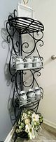 Full view of black metal scrollwork etagere shelf with three tiers
