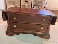 Front view of coffee table showing drawers, brass pulls, drop-leaf sides folded down