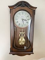 Front view of Bulova wall clock showing case, dial, glass door and pendulum