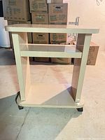 Front view of light beige rolling cart showing top, middle shelf, base, and casters