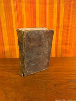 Front and spine of worn leather book standing upright
