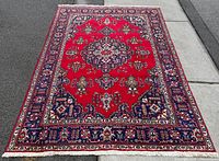 Full view of red Persian Tabriz rug laid flat showing overall design and size