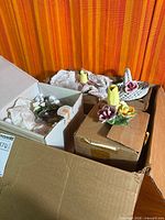 Open shipping box showing several smaller boxes and exposed porcelain floral pieces