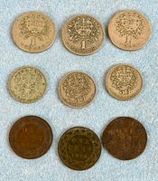 Front view of nine coins: 3 Portuguese 1 Escudo, 2 Portuguese 50 Centavos, 3 Canadian large cents