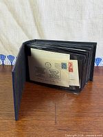 Closed album standing open displaying first day covers in plastic sleeves