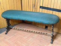 Full view of bench showing cast iron base, twisted stretcher and teal upholstered seat