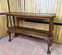 Angled front and side view showing top, lower shelf, supports, and ball-and-claw feet