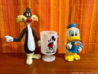 Front view of Sylvester figure, Mickey mug and Donald bank