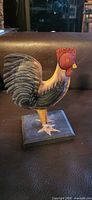Front view of painted metal rooster on square base