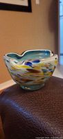 Full view of art glass bowl showing teal interior and multicolor speckled exterior