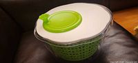 Salad spinner assembled showing clear bowl, white lid, green knob