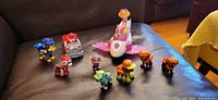 Group shot of all 11 Paw Patrol figures and vehicles on sofa