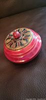 Closed box showing red lacquer and painted lid