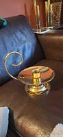 Overall view of polished brass chamberstick candle holder on sofa