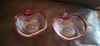 Two clear pressed glass apple bowls side by side showing red rim and stems