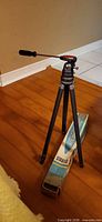Tripod extended mid-height beside original box