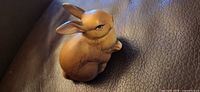 Front angled view of brown ceramic rabbit on leather surface
