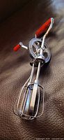Full view of egg beater showing beaters, handle, crank knob