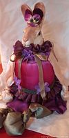 Front view of fabric rabbit doll in magenta and purple attire