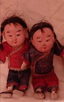 Two Asian-style dolls standing together showing outfits and wear
