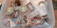 Plastic bin with packaged pendants, faux pearls, metal clip and assorted findings