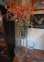 overall view of stand, tall vase with stones and faux florals, three other glass vases