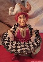 Seated jester doll wearing black-white harlequin skirt, burgundy bodice, brown-cream jester hat, Katherine tag visible
